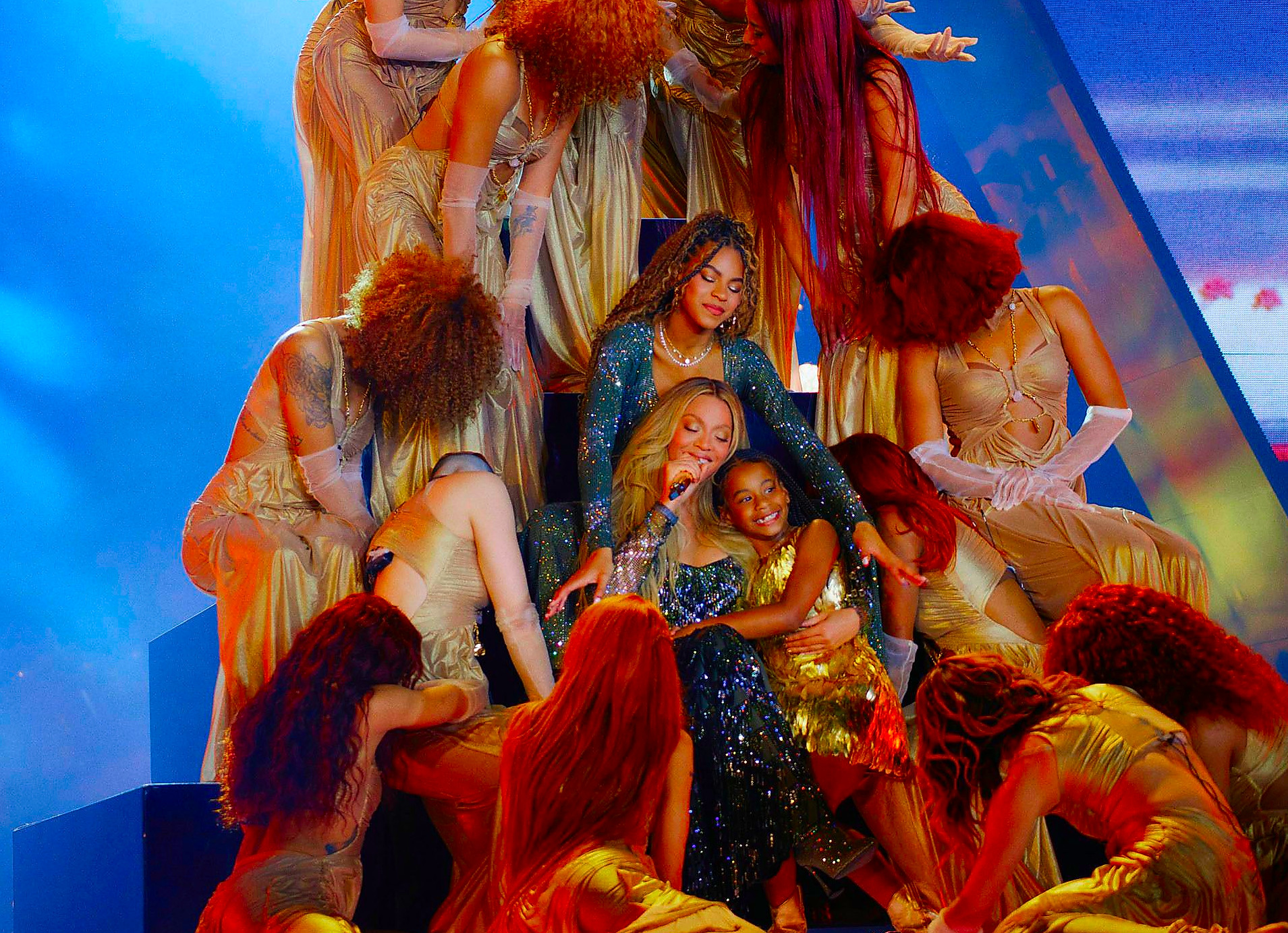 performance featuring multiple dancers in elaborate costumes surrounding a central figure