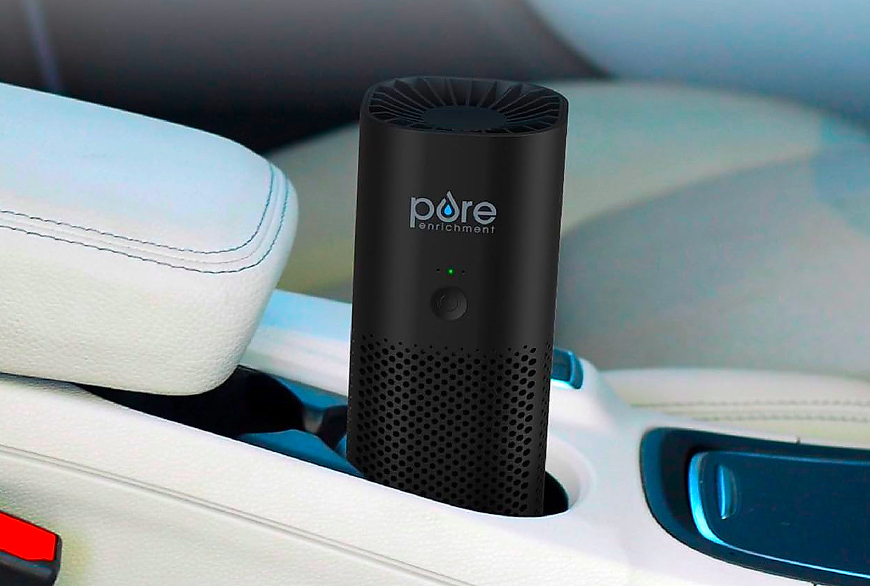A portable air purifier in the cup holder of a car.