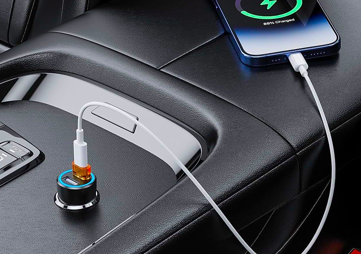 A smartphone charges in a car using a USB-C cable connected through a USB to USB-C adapter plugged into the car's USB port.