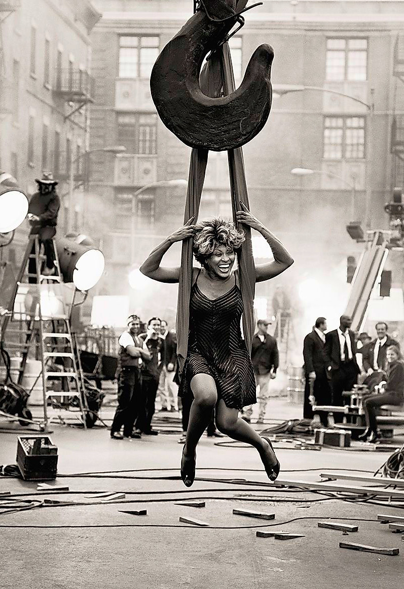 tina turner smiling while being suspended on a swing by a crane