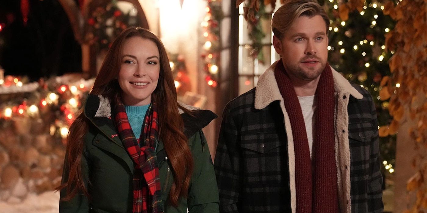 Lindsay Lohan and Chord Overstreet stand outside a festive doorway in Falling for Christmas. 