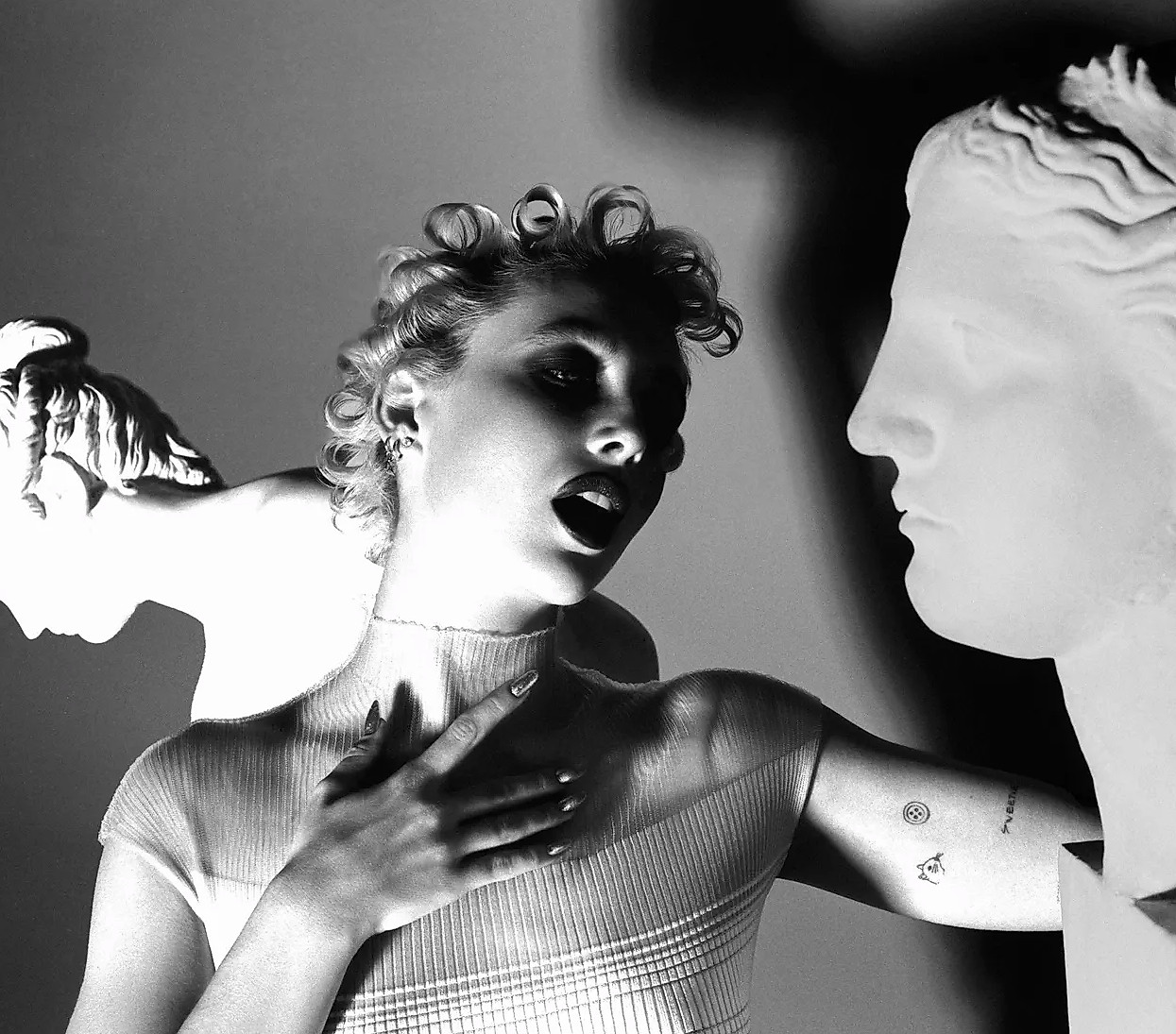 Emma Chamberlain emoting around statues in a sheer dress