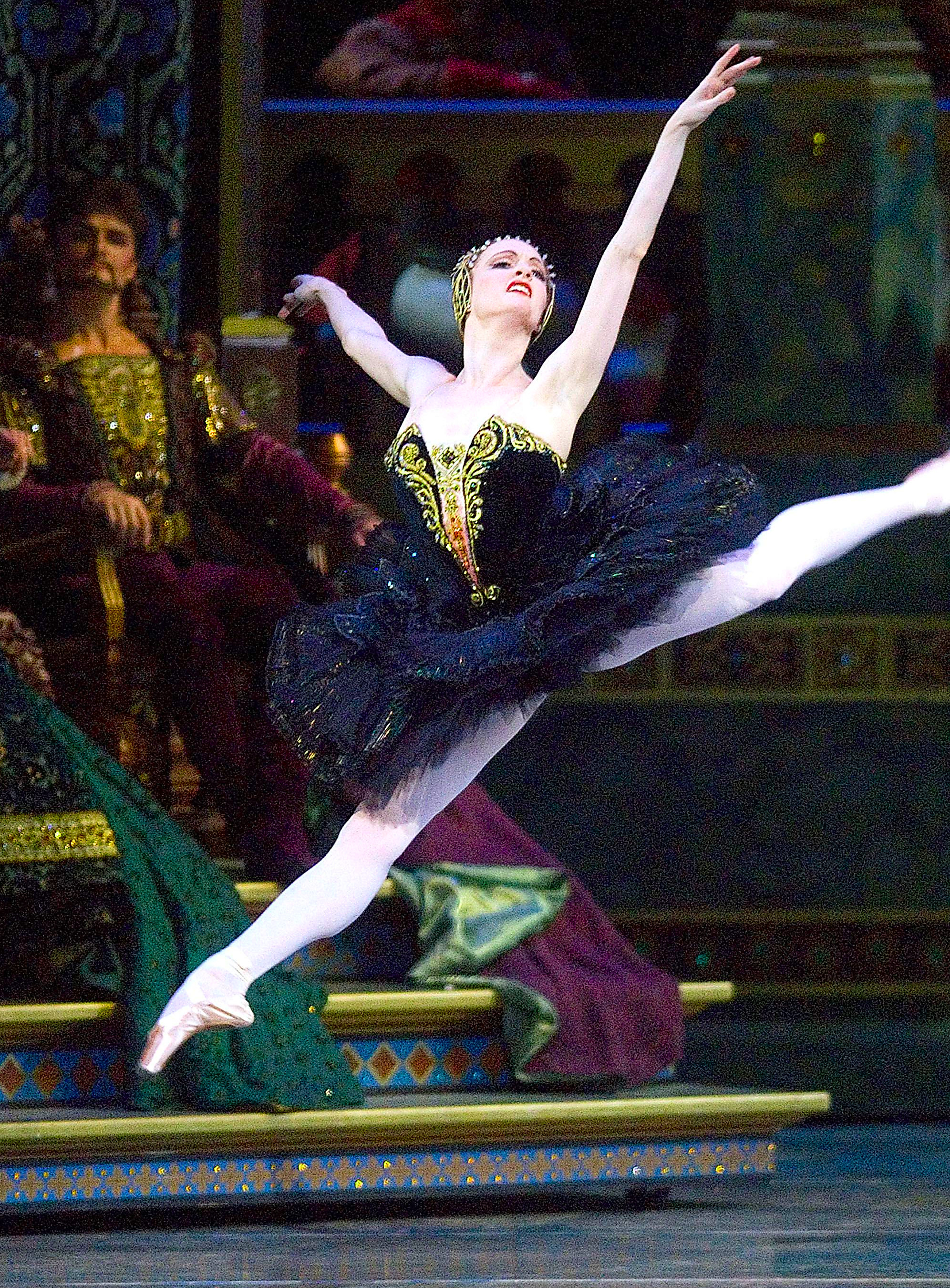 a ballet dancer performing an impressive leap in a theatrical setting