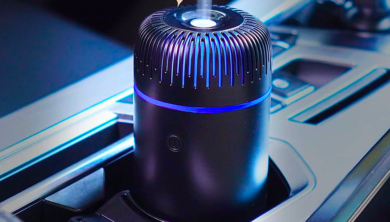 A small, black, cylindrical car humidifier placed in the cup holder of a car.