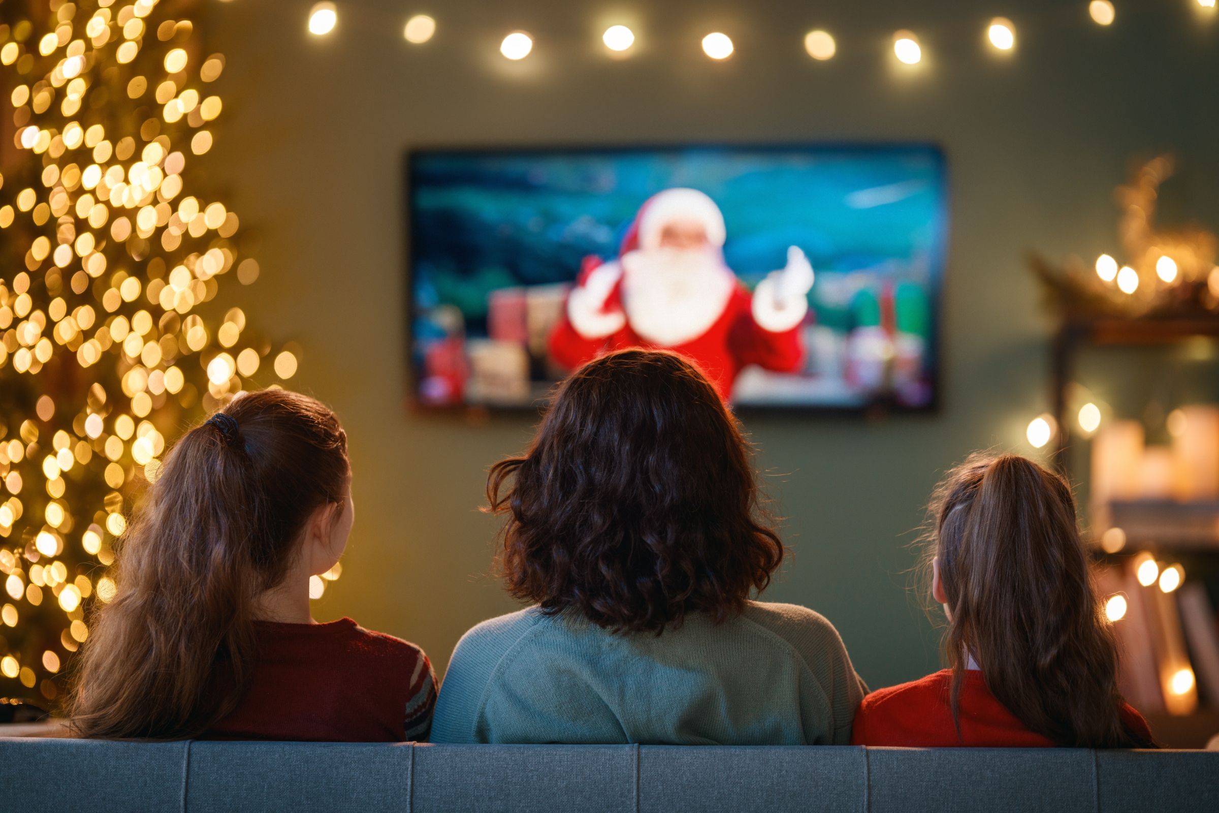 Family sitting in front of the TV at Christmas.