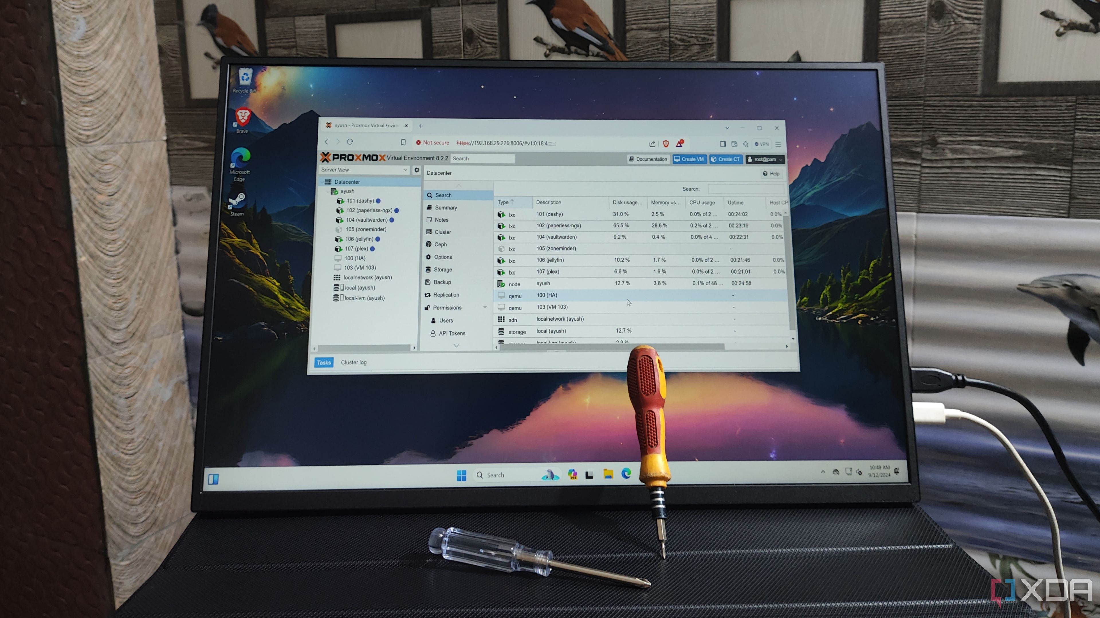 The Proxmox UI running on a portable monitor with two screwdrivers resting against it
