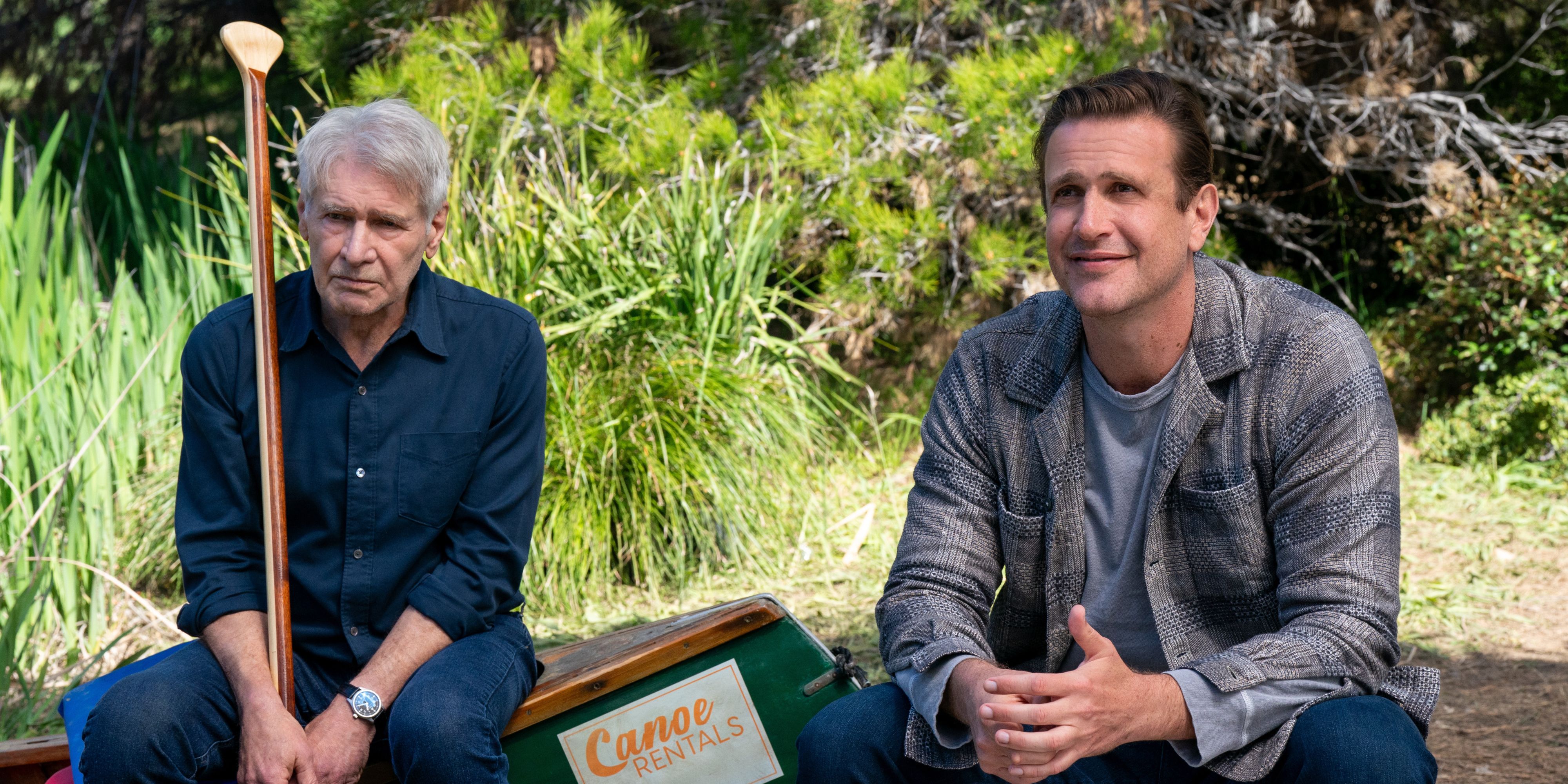 Harrison Ford and Jason Segel sitting in a (beached) canoe and Ford is holding a paddle in Shrinking Season 2