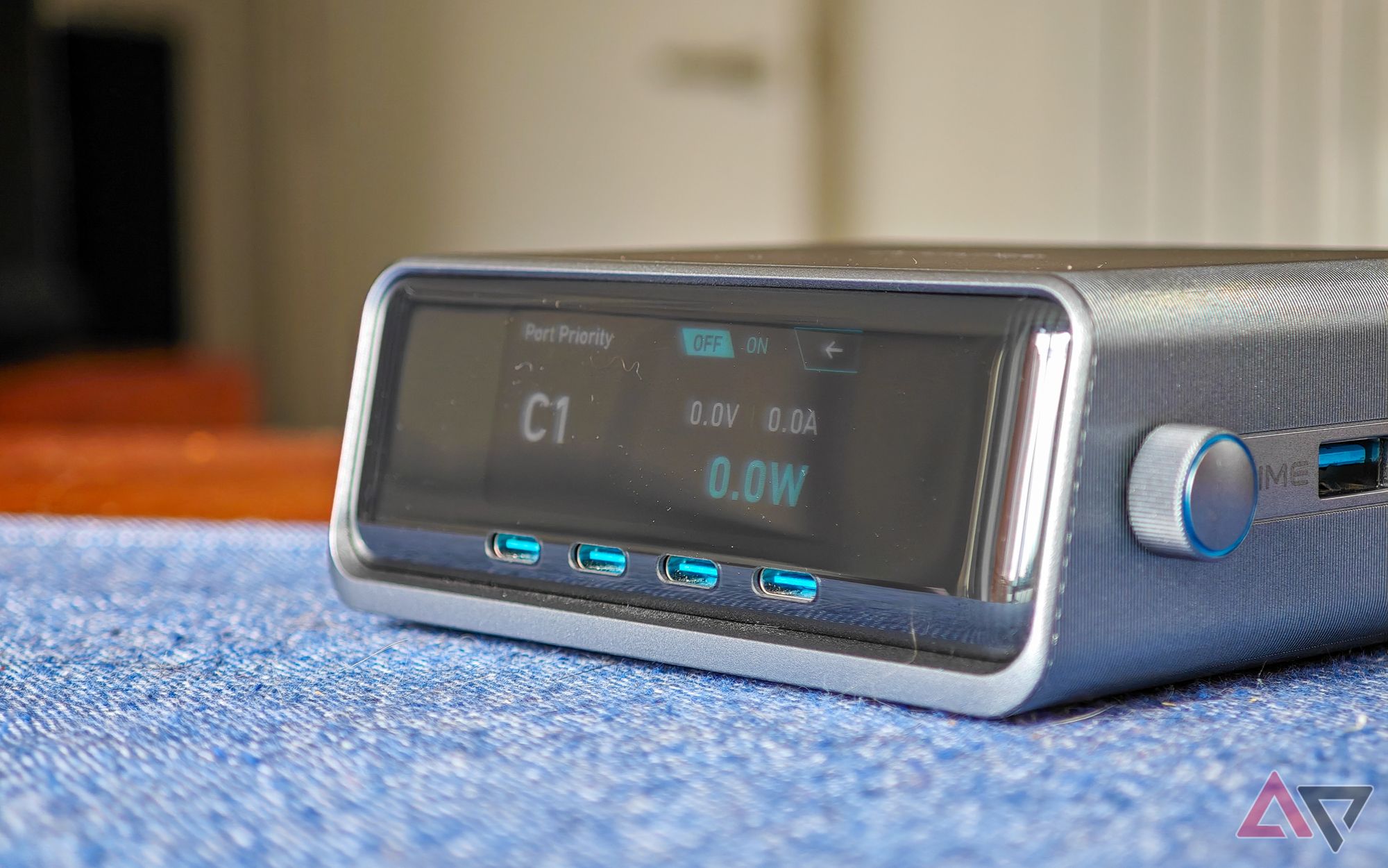 Anker Prime 250W desktop charger sitting on a blue cloth on a wooden table with nothing plugged in but the screen active