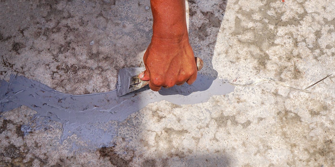 Hand holding trowel repairing concrete crack