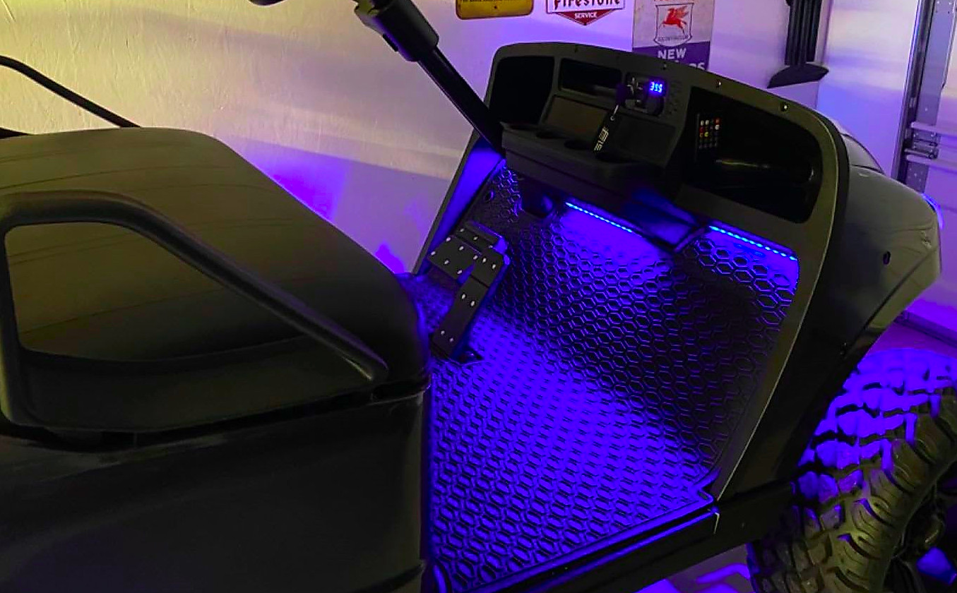 A black golf cart with blue LED lights installed on the floorboard and under the cart.