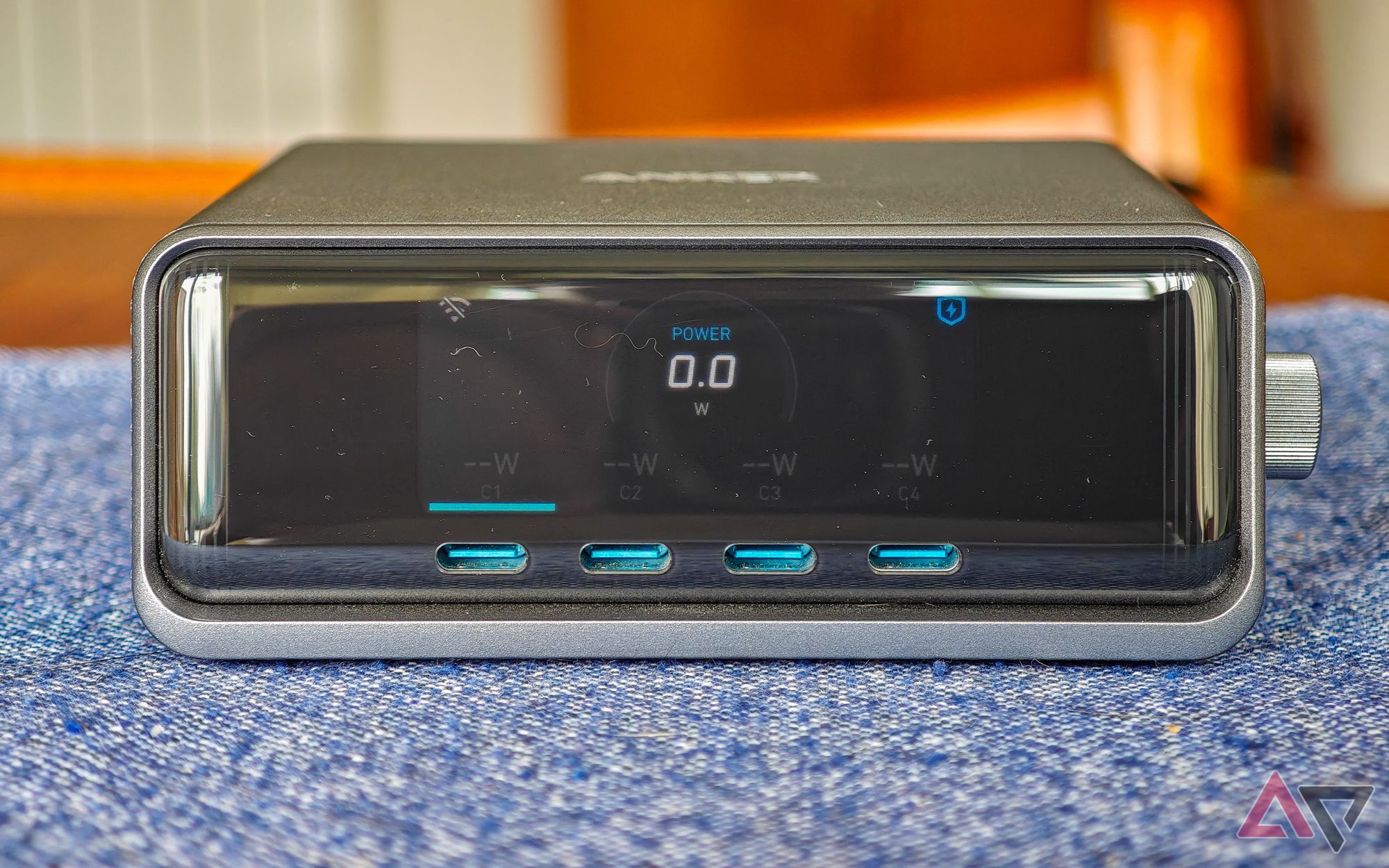 Anker Prime 250W desktop charger sitting on a blue cloth on a wooden table, seen from the front with nothing plugged in