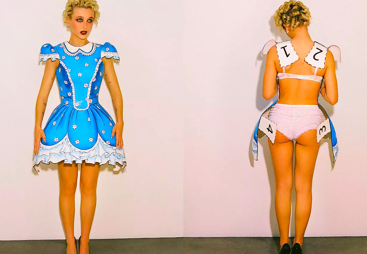 Emma Chamberlain in a paper doll dress from the front and expose undergarments from behind.